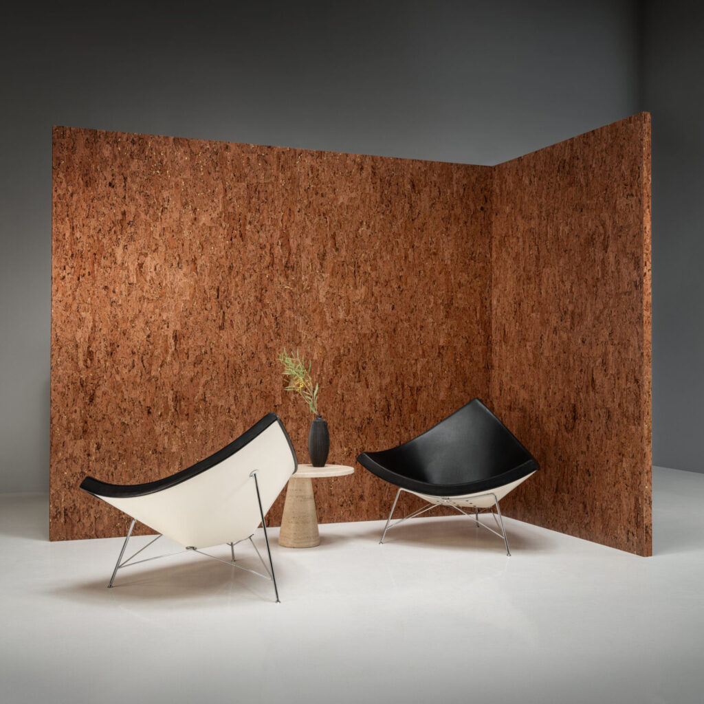 Twee moderne stoelen en een bijzettafel staan voor een wand bekleed met Arte-behang Alentejo Cork 90595.