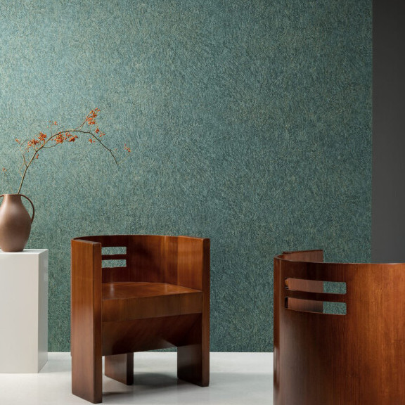 Moderne interieursetting met Arte behang Boutique Canyon 90550, twee houten designstoelen en een vaas met takken op een witte sokkel.