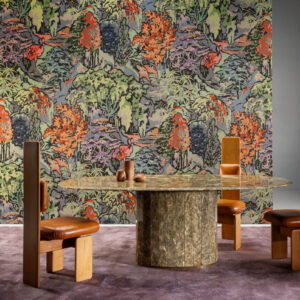 Sfeervolle interieursetting met Boutique Riverbank 90515 behang van Arte, een kleurrijk patroon met bomen en vogels, achter een ronde tafel en designstoelen.
