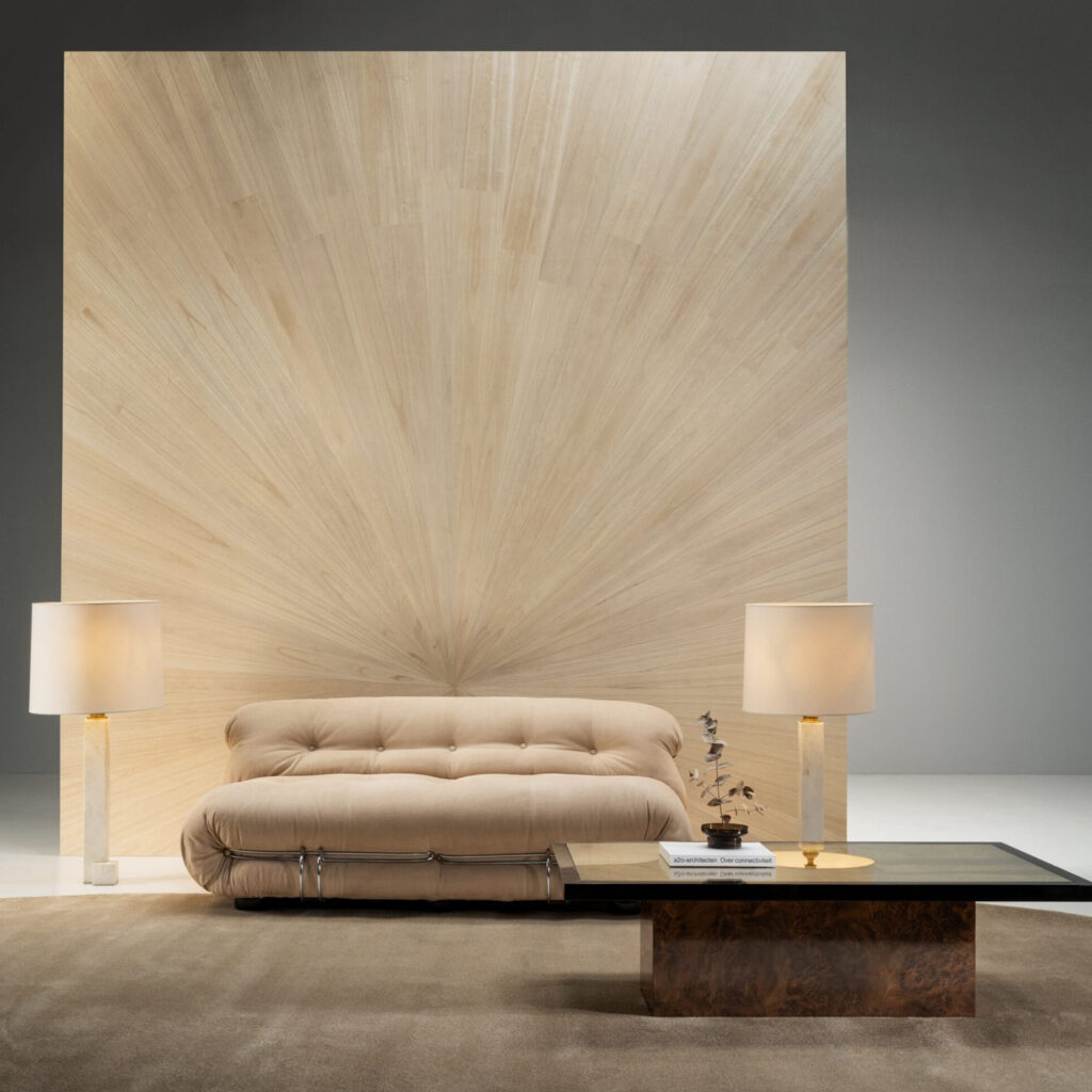 Beige designbank voor een wand met zonnestraalpatroon van Arte behang Boutique Sunburst 90510.