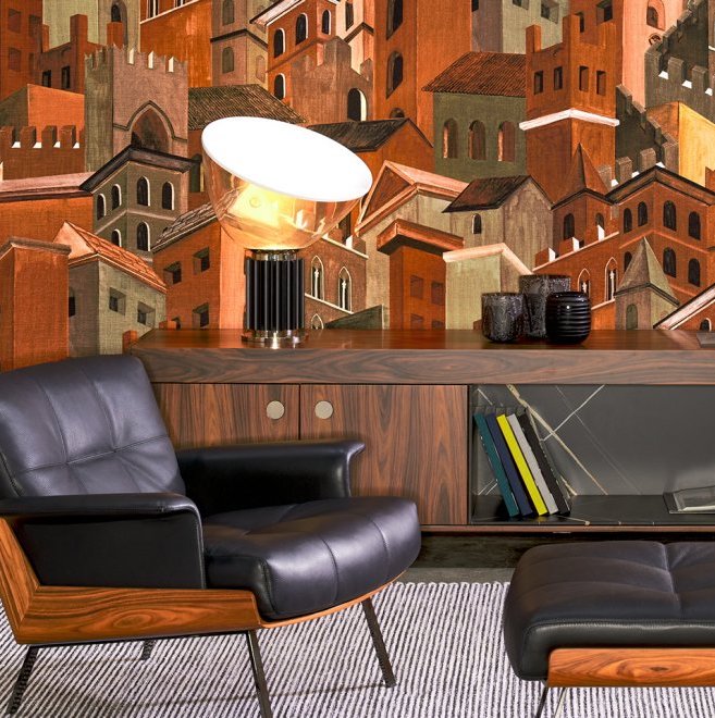 Moderne zithoek met een donkerhouten dressoir en zwart leren fauteuil, voor een sfeervol Arte Città di Castello behang met rode stadshuizen.