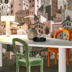 Moderne eettafel met kleurrijke stoelen en decoratieve muur met Arte-behang Città di Castello in een stadslandschapmotief.