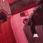 Detail van het Arte behang Città di Castello 97682 met abstracte architectonische vormen in rood- en roze tinten.