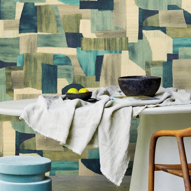 Moderne eettafel met linnen tafelkleed voor een muur met kleurrijk Arte Essentials Costura Urban 57600 behang in patchworkstijl.
