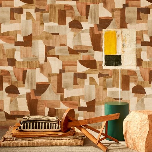 Interieur met Arte Essentials Costura Urban 57601 behang in aardetinten, houten meubelen en een moderne lamp.