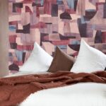 Sfeervolle slaapkamer met het abstracte Arte Essentials Costura Urban 57603 behang in paars-roze tinten.