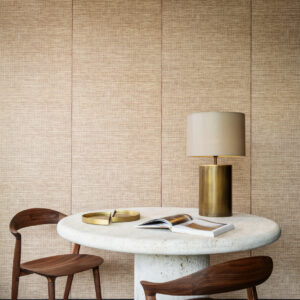 Interieur met Arte-behang Essentials Les Naturels Le Raphia Tissé 26740, ronde stenen tafel, houten stoelen en gouden tafellamp.