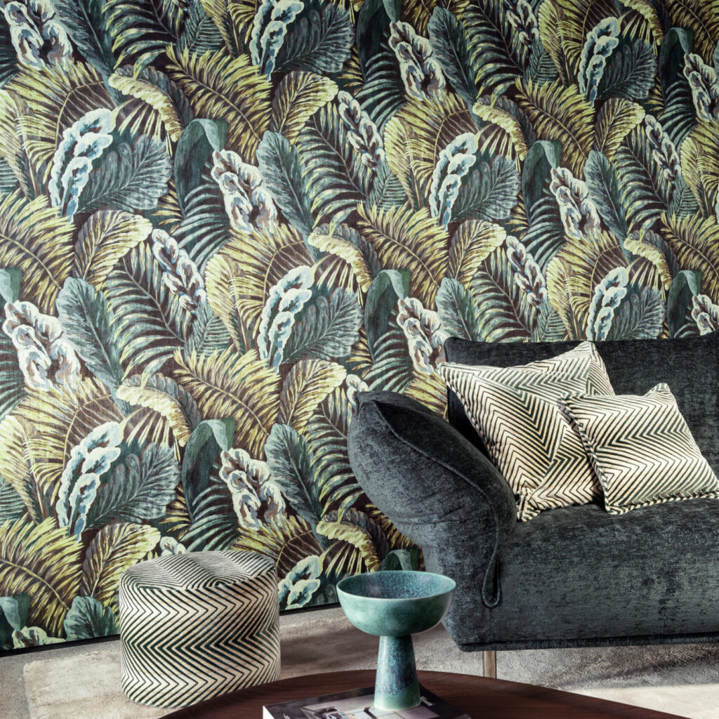 Interieur met Arte-behang Essentials Les Naturels Verdure 26761 met tropisch bladerpatroon, een donkergroene fluwelen bank en zwart-wit grafische kussens.