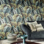 Interieur met Arte-behang Essentials Les Naturels Verdure 26761 met tropisch bladerpatroon, een donkergroene fluwelen bank en zwart-wit grafische kussens.