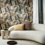 Stijlvol interieur met een gebogen crèmekleurige bank en tropisch Arte-behang Essentials Les Naturels Verdure 26762 op de achtergrond.