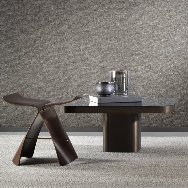 Moderne interieursetting met Arte-behang Essentials Les Nuances Chanderi, een sculpturale donkerbruine stoel en een lage tafel met decoratieve objecten.