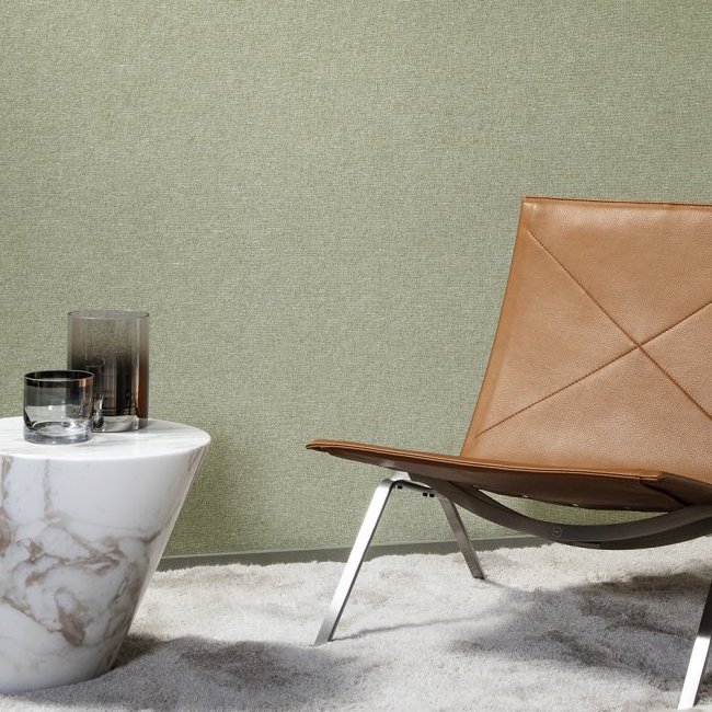 Designinterieur met Arte-behang Essentials Les Nuances Chanderi, een leren designstoel en een marmeren bijzettafel op een lichtgrijs vloerkleed.