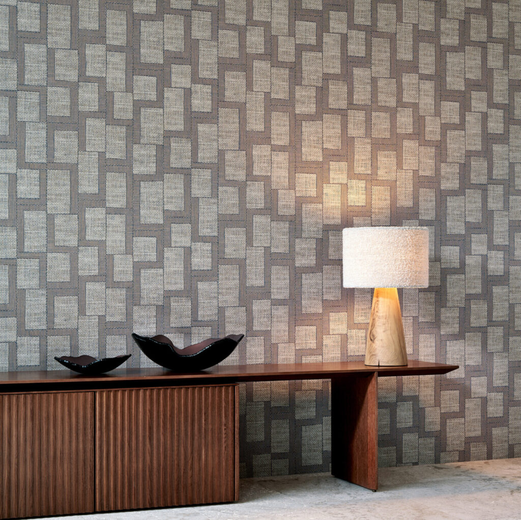 Interieur met Arte behang uit de Essentials Totem collectie, type Esparto Africano, met geometrisch patroon, houten sidetable, decoratieve schalen en een tafellamp.