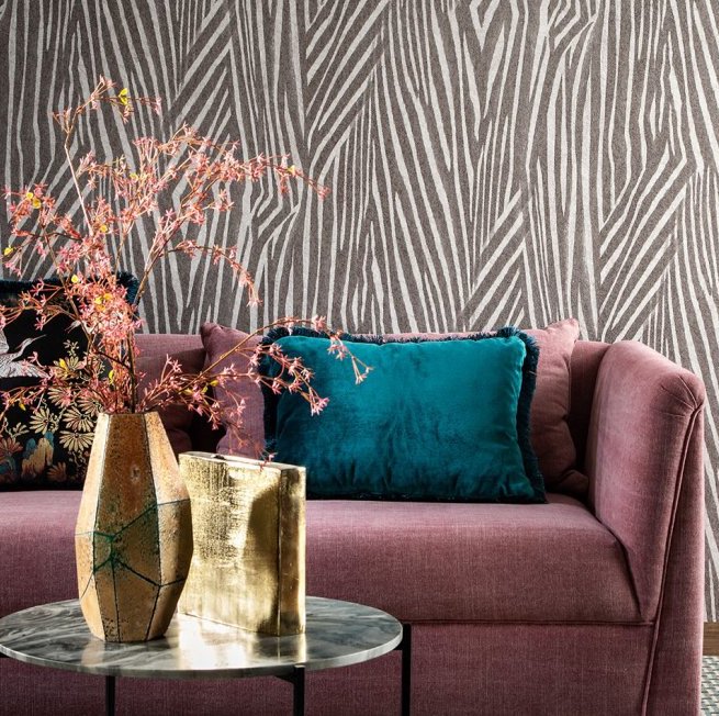 Moderne woonkamer met Arte-behang Essentials Travellers Damara, een roze bank en kleurrijke accessoires.