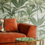 Oranje fluwelen bank met kussens voor tropisch Arte-behang uit de Essentials Travellers-collectie met palmbladmotief.