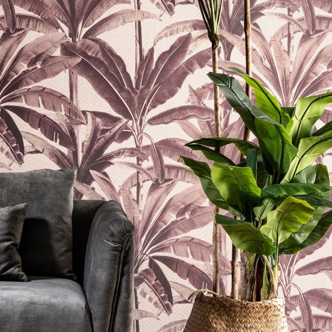 Woonkamerhoek met een grijze fauteuil, een groene plant in mand en Arte Essentials Travellers Palmera behang met palmmotief op de achtergrond.