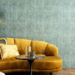 Gele fluwelen bank met sierkussens voor een muur met groen Arte Essentials Travellers Talamanca behang.