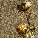 Goudkleurige bloemvormige lamp voor een wand met Arte-behang uit de Essentials Travellers Tantor-collectie.