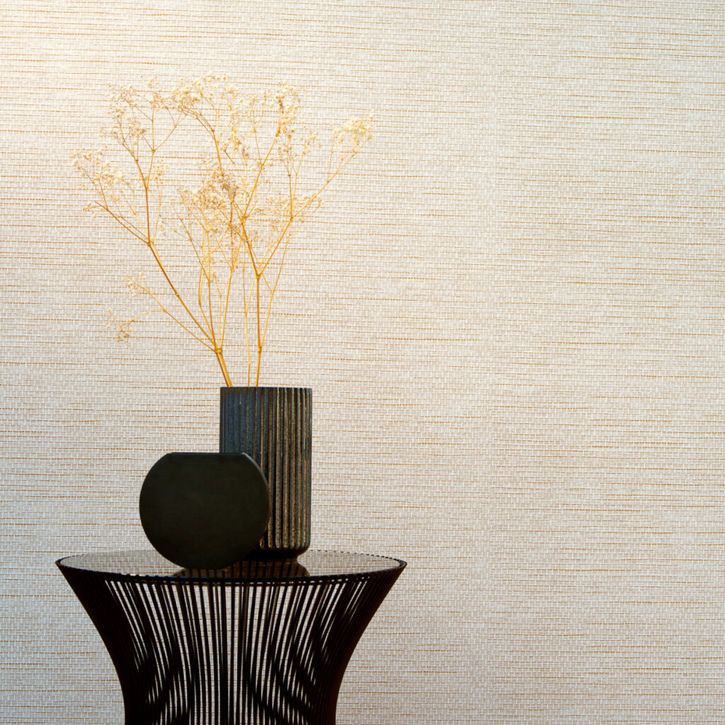 Stijlvolle interieursetting met Arte behang uit de Essentials Palette collectie, model Le Papier Tissé 60504B, met een decoratieve vaas en gedroogde takken op een design bijzettafel.