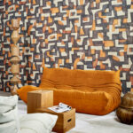 Moderne woonkamer met een okergele bank en Arte-behang uit de Essentials Totem Ecoline 18900 collectie met abstract geometrisch patroon.