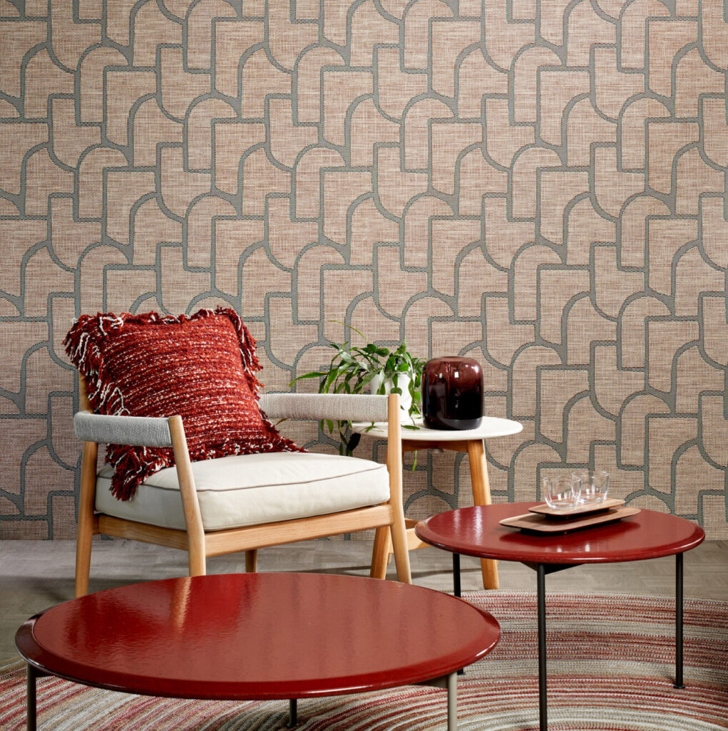 Interieur met Arte-behang Essentials Totem Esparto Iberico, een houten stoel met rood kussen, rode salontafels en een plant op een bijzettafel.