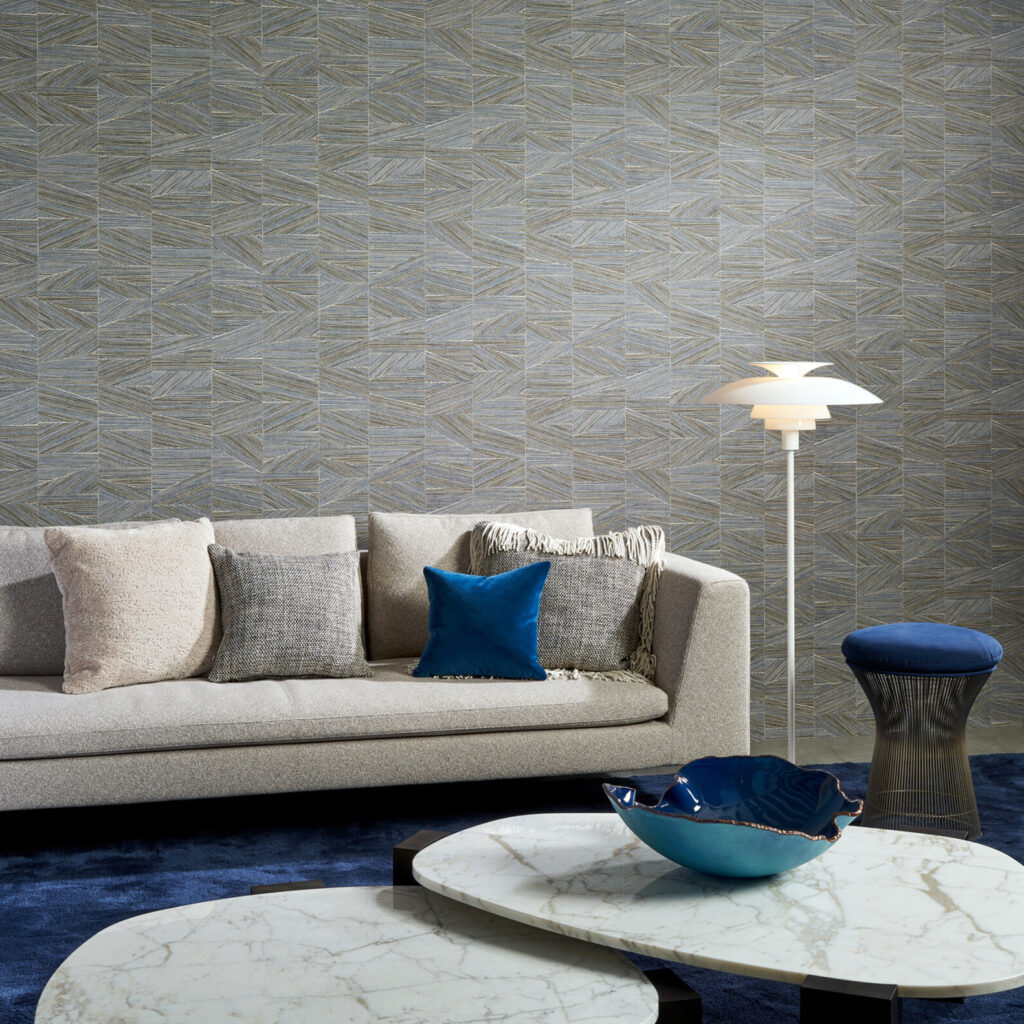 Moderne woonkamer met Arte Essentials Totem Infinity 18930 behang, een beige bank, blauwe accenten en marmeren salontafels.