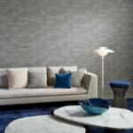 Moderne woonkamer met Arte Essentials Totem Infinity 18930 behang, een beige bank, blauwe accenten en marmeren salontafels.