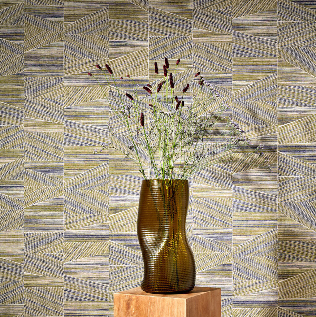 Bruine vaas met bloemen op houten sokkel voor geometrisch Arte-behang uit de Essentials Totem Infinity 18932 collectie.