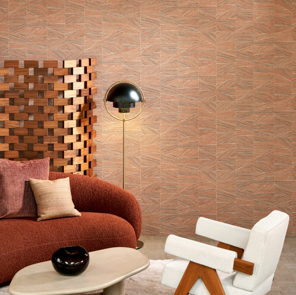 Moderne zithoek met Arte-behang Essentials Totem Infinity 18935 in aardetinten, een ronde rode bank, witte designstoel en houten roomdivider.