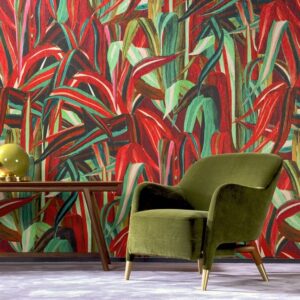 Groen fluwelen fauteuil en houten bijzettafel met lamp staan voor kleurrijk Arte-behang uit de Expedition Java-collectie met een tropisch bladerpatroon.