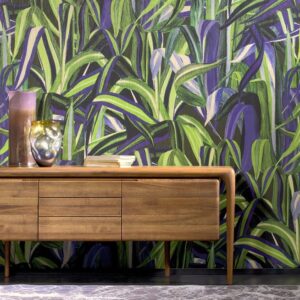 Houten dressoir voor een kleurrijk groen-paars Arte Expedition Java behang met tropisch bladerpatroon.