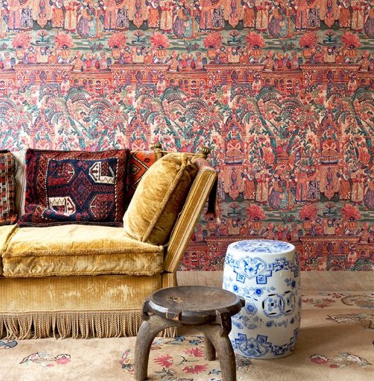 Kleurrijk interieur met Arte Gitane Emperador behang, een fluwelen gele bank en etnische decoratieve accenten.