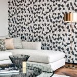 Moderne woonkamer met een lichtgrijze bank en een geometrisch Arte-behang uit de Insolence Blast-collectie op de achterwand.