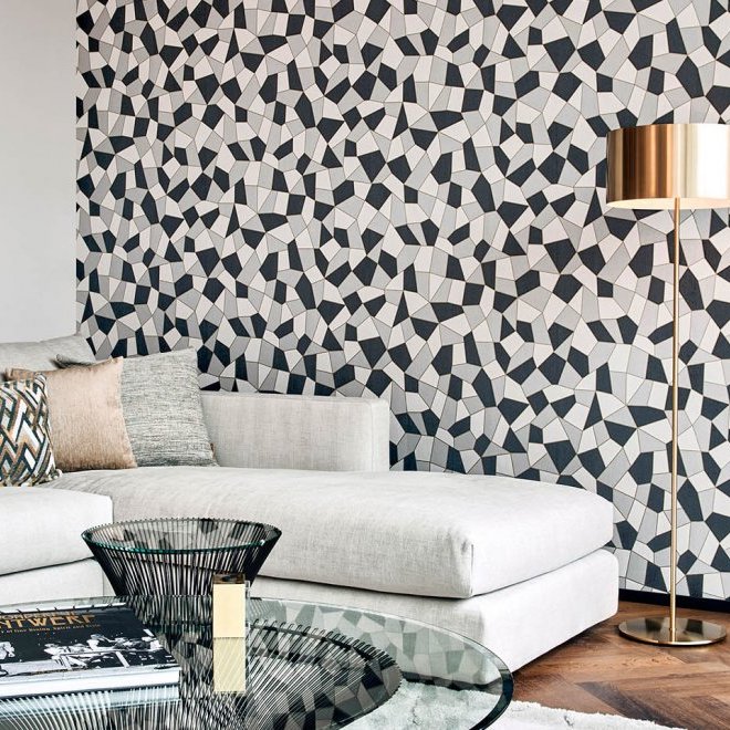 Moderne woonkamer met een lichtgrijze bank en een geometrisch Arte-behang uit de Insolence Blast-collectie op de achterwand.