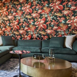 Donkergroene zithoek met goudkleurige salontafel voor een muur bekleed met kleurrijk Arte-behang Insolence Grow 346401 met botanisch patroon.