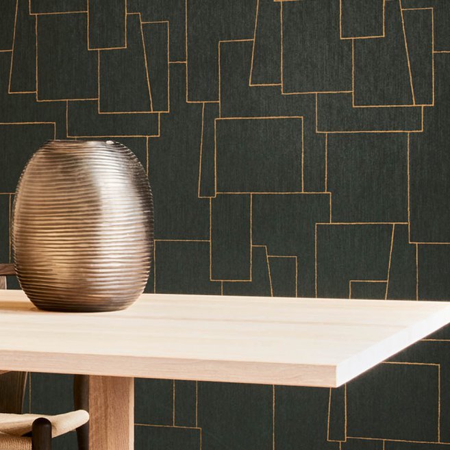 Arte-behang Insolence Nerve met goudkleurig lijnenspel op donker oppervlak achter een licht houten tafel met een metallic vaas.