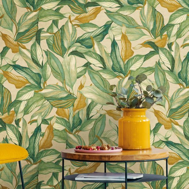 Sfeervolle interieursetting met het Arte behang JV800 Tierra Mediterraneo 6611 met groen-geel bladmotief, een gele vaas met takken en een houten tafel.