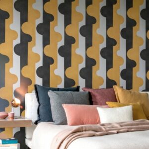 Sfeervolle slaapkamer met Arte-behang Joy Puzzle of Passion in geel, zwart en grijs met decoratieve kussens op het bed.