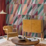 Interieur met Arte-behang Joy Print in kleurig geometrisch patroon, houten meubels en rode gordijnen.