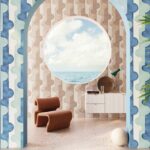 Interieur met Arte-behang Joy Puzzle of Passion in blauw en beige tinten, met ronde raamopening en uitzicht op zee.