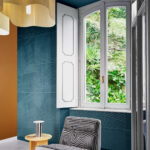 Interieur met Arte-behang Kanso Shibumi 72530 in blauwgroen reliëfpatroon, naast een raam met uitzicht op weelderig groen.