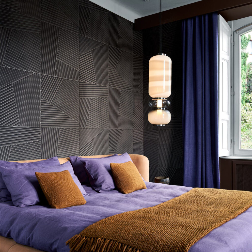 Sfeervolle slaapkamer met Arte-behang Kanso Shibumi 72532, een paarse sprei, okergele accenten en moderne hanglamp.