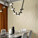 Moderne eethoek met Arte-behang Kanso Yugen 72502, een marmeren tafel, designverlichting en warme oranje gordijnen.