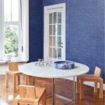 Moderne eetkamer met Arte Kharga 74026 leerlook behang in diepblauw en minimalistisch houten meubilair.