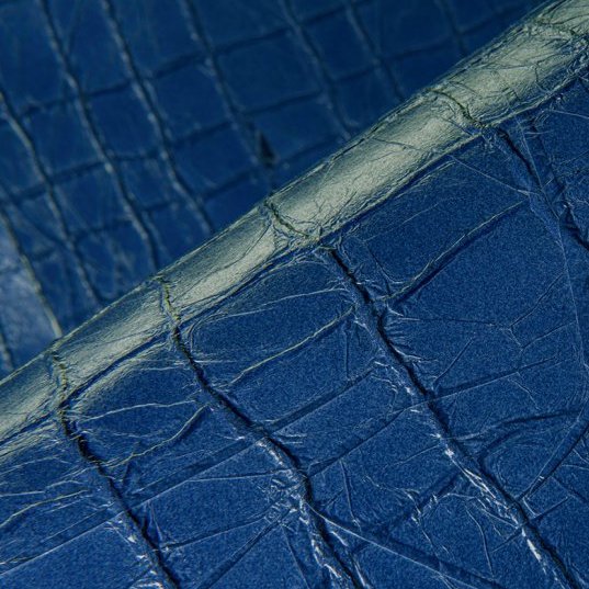 Close-up van blauw Arte Kharga 74026 leerbehang met een krokodillenhuidstructuur.