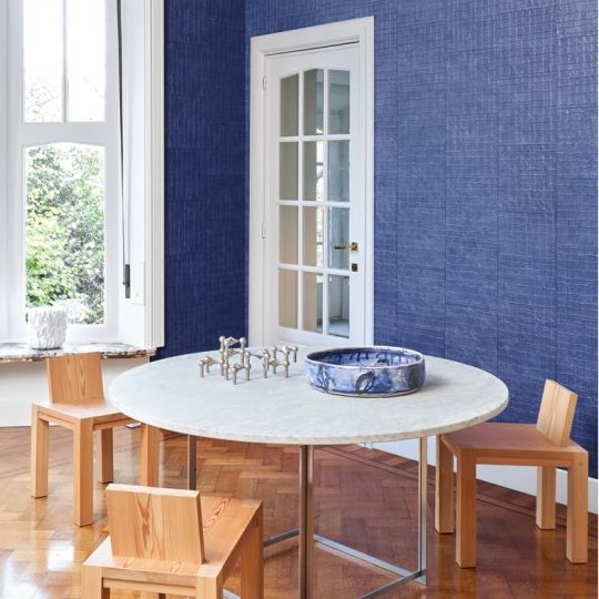 Moderne eetkamer met Arte Kharga 74026 leerlook behang in diepblauw en minimalistisch houten meubilair.