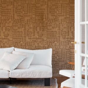 Woonkamer met Arte Kharga Barkhan 74001 ochre behang en een witte bank met kussens.