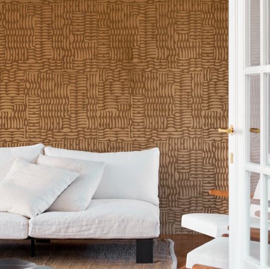 Woonkamer met Arte Kharga Barkhan 74001 ochre behang en een witte bank met kussens.
