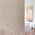 Sfeervolle kamer met Arte behang Kharga Bayuda 74041 in de kleur sunrise copper met een golvend, glinsterend patroon.