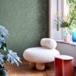 Witte designfauteuil bij een raam met groen Arte Kharga Gobi 74032 behang op de achtergrond.
